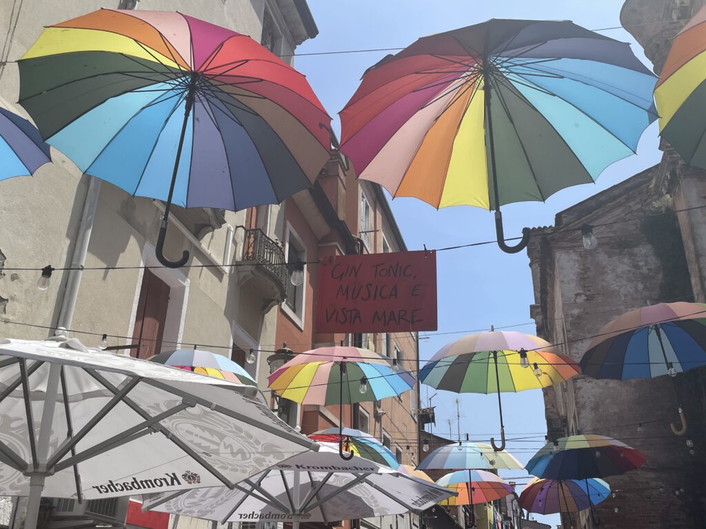 Bunte Regenschirme über einer Straße in Chiogga in Italien.