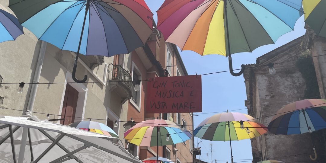 Bunte Regenschirme über einer Straße in Chiogga in Italien.